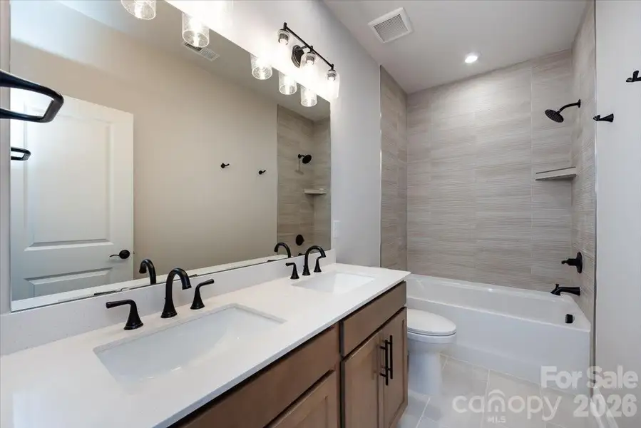 Secondary dual vanity bathroom with tiled walls above the tub Secondary dual vanity bathroom with tiled walls above the tub