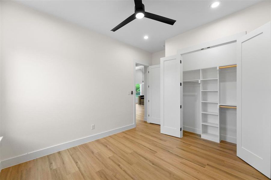 Bedroom featuring wood-finish flooring, white walls, and a contemporary black ceiling fan