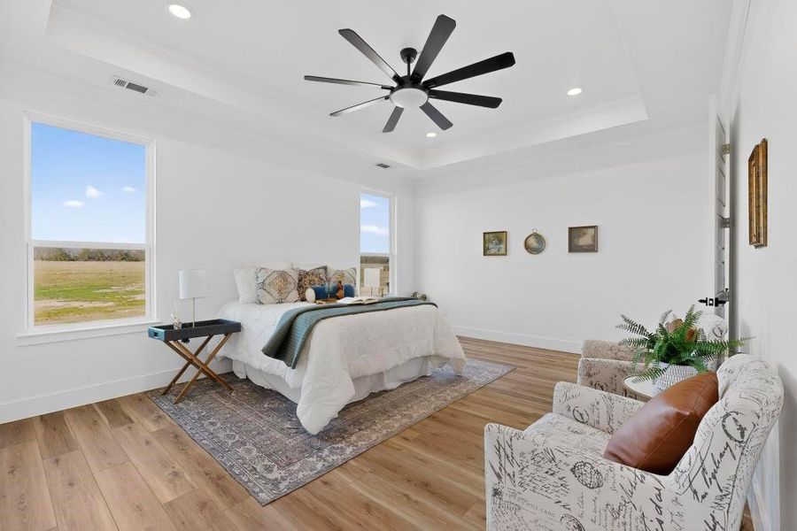 Bedroom with light wood-style floors, ceiling fan, recessed lighting, and a tray ceiling Bedroom with light wood-style floors, ceiling fan, recessed lighting, and a tray ceiling