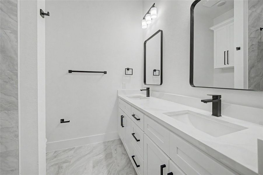 Beautifully finished primary bath with sleek black hardware, large walk-in shower, and designer lighting.