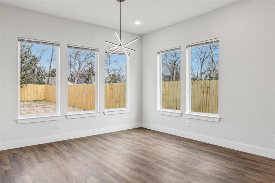 Unfurnished dining area with an inviting chandelier, dark hardwood / wood-style flooring, and plenty of natural light