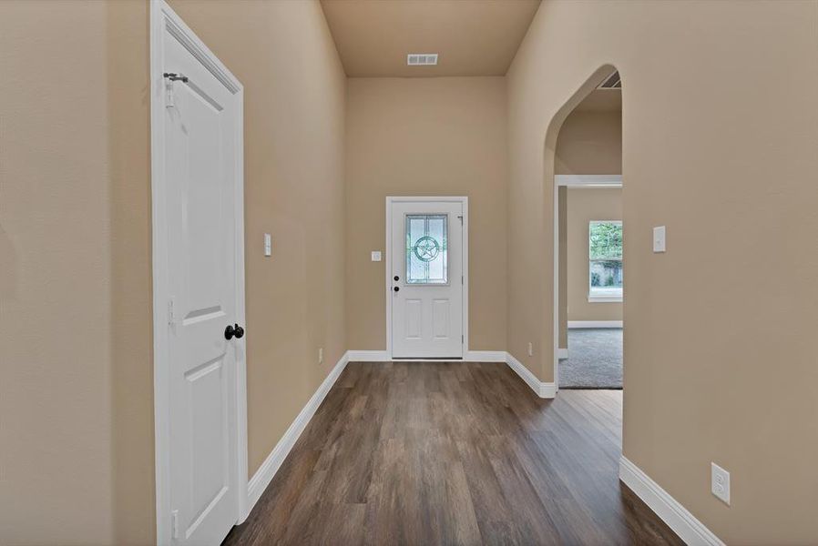 Foyer featuring arched walkways, baseboards, visible vents, and dark wood-style floors Foyer featuring arched walkways, baseboards, visible vents, and dark wood-style floors
