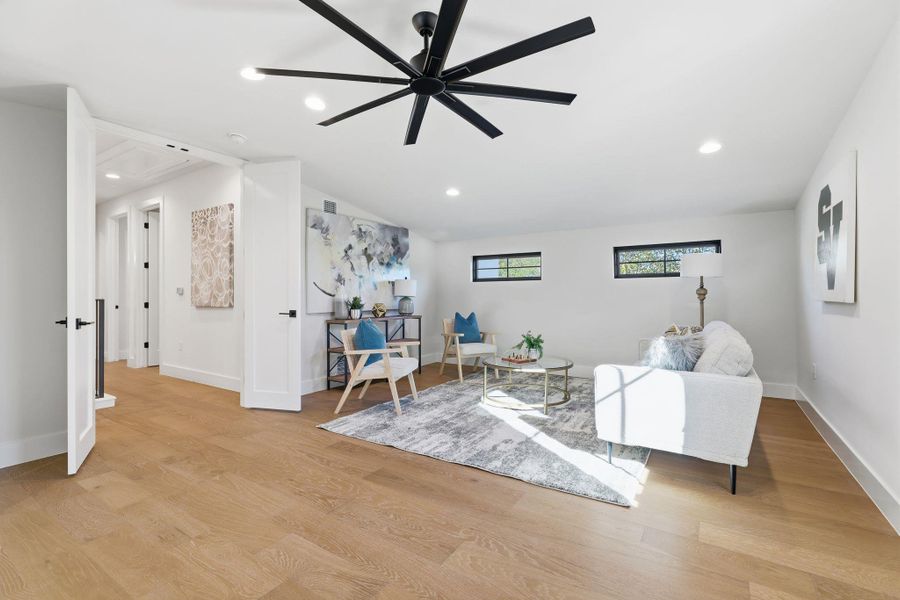 Living area with light wood-type flooring, a ceiling fan, vaulted ceiling, and recessed lighting