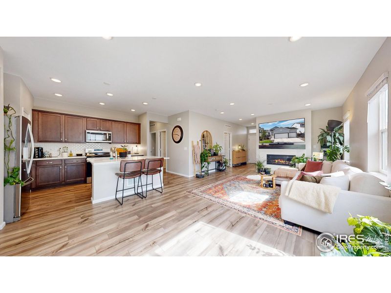 Spacious kitchen featuring stainless steel appliances, a gas range and oven, quartz countertops including a kitchen island and a custom tile backsplash.