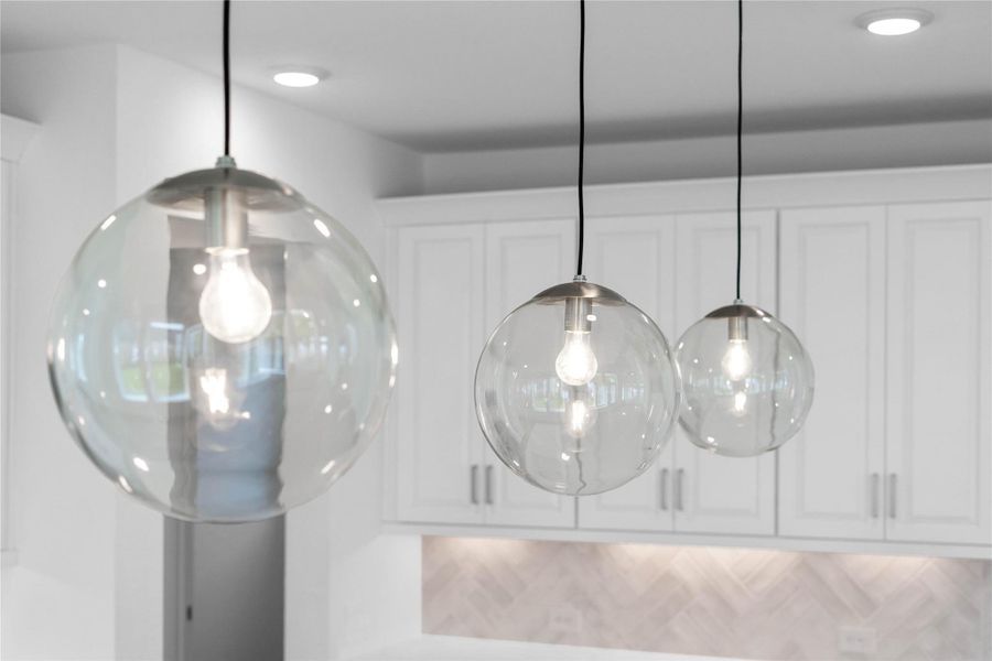Three eye-catching Atwell clear glass globe pendant lights that provide elegant task lighting over the kitchen island.