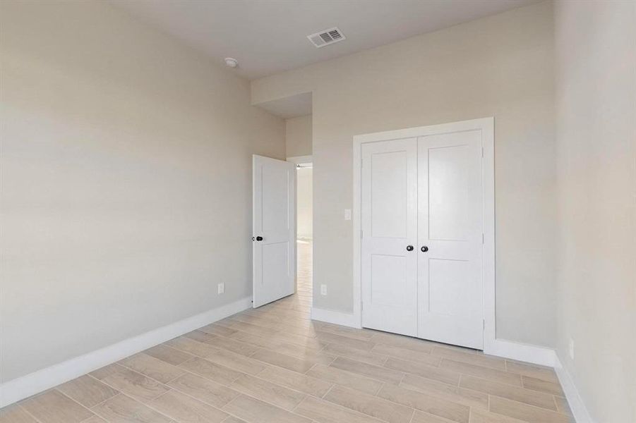 Unfurnished bedroom with visible vents, baseboards, a closet, and wood tiled floor