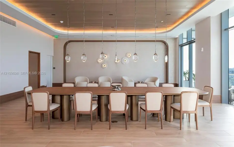 Wood-finish flooring, recessed ceiling with perimeter accent lighting, wood-paneled ceiling inlay, a series of glass pendant light fixtures, and floor-to-ceiling windows