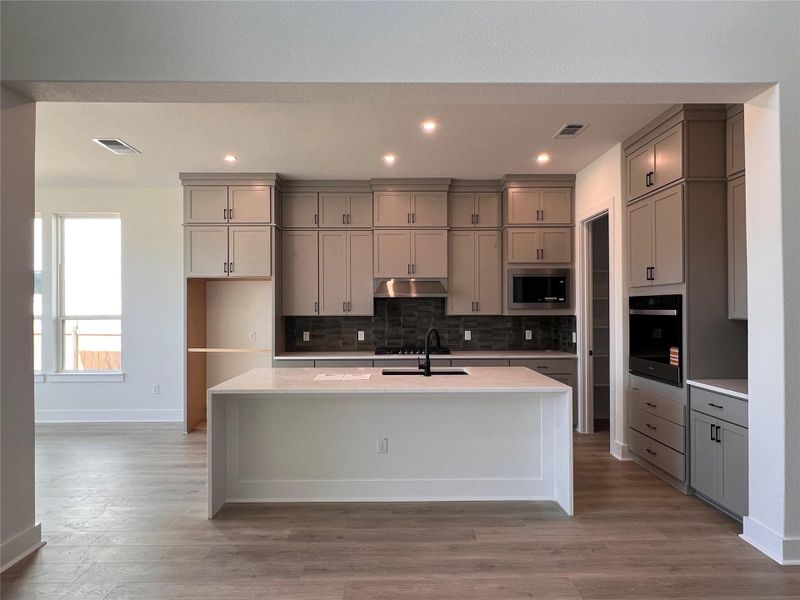 Kitchen with light stone countertops, gray cabinetry, light wood-type flooring, and recessed lighting
