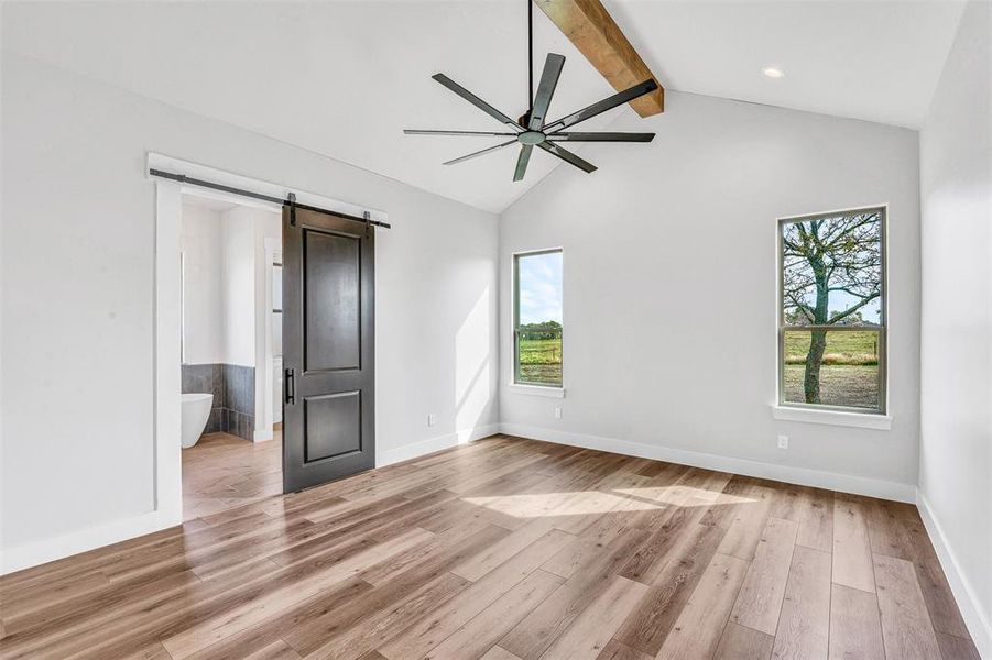 Unfurnished bedroom with light wood-type flooring, a barn door, and multiple windows