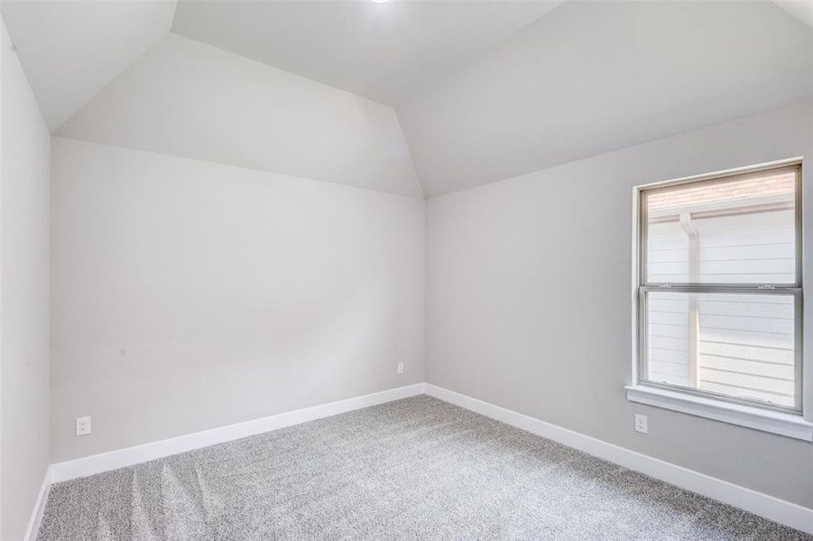 Secondary bedroom featuring vaulted ceiling and carpet flooring