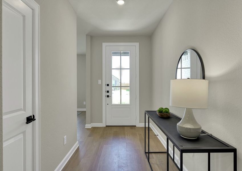 Foyer featuring the front door, a styled console table with lamp and mirror, and wood-look flooring.