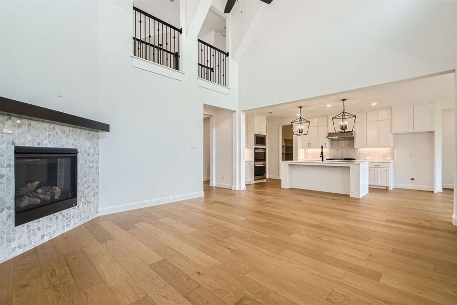 Unfurnished living room with a high ceiling, sink, and light hardwood / wood-style floors