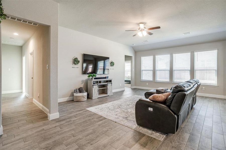 Living room with ceiling fan, light wood-style tile flooring