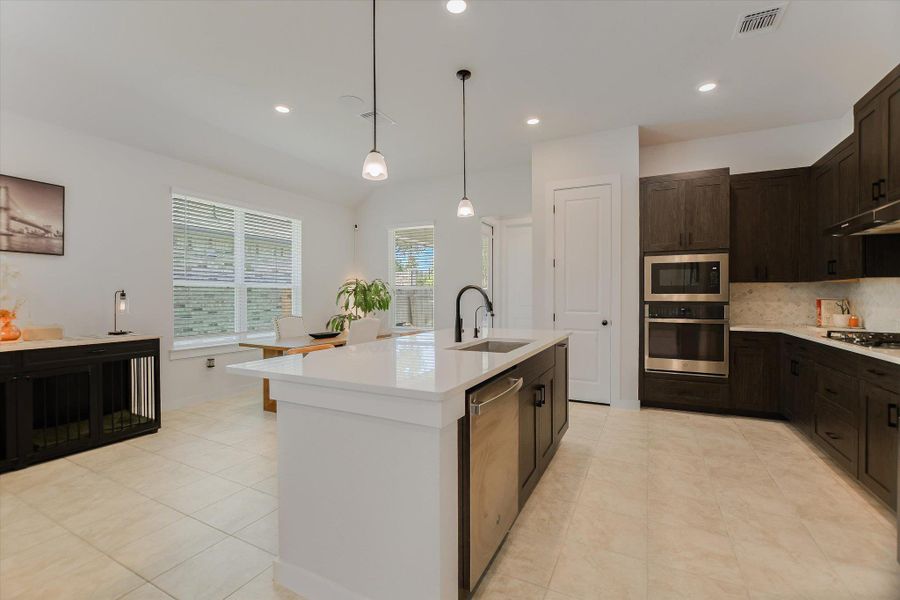 An open-concept culinary space provides seamless entertaining with a central island and contemporary fixtures. An open-concept culinary space provides seamless entertaining with a central island and contemporary fixtures.