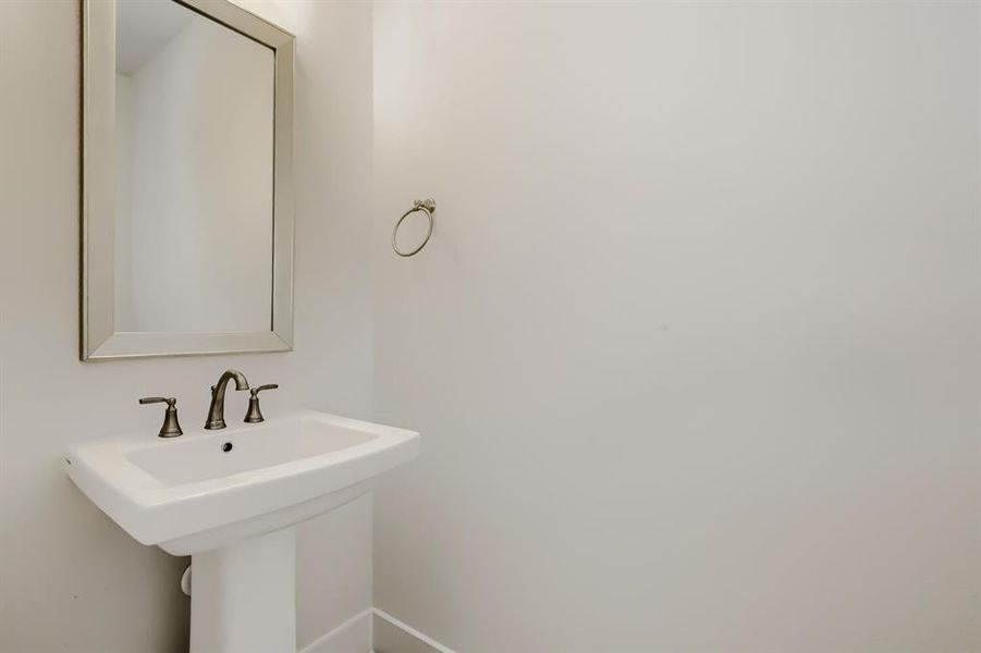 Pedestal sink with a wide basin, bronze-finish faucet, and coordinating towel ring