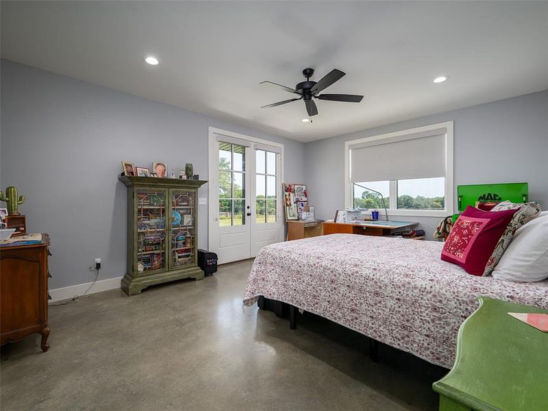 Bedroom featuring access to exterior, finished concrete floors, ceiling fan, and recessed lighting Bedroom featuring access to exterior, finished concrete floors, ceiling fan, and recessed lighting