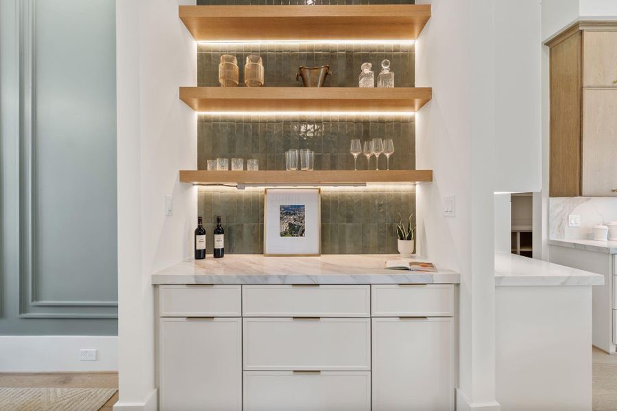 Adjacent to the dining room, a custom-built bar area features white oak shelving, integrated lighting, and sleek cabinetry, offering both function and a designer touch. A closer look highlights the detailed craftsmanship, illuminated shelving, and seamless integration of materials, creating a sophisticated space for entertaining.