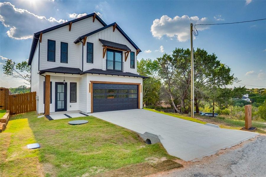 Modern inspired farmhouse featuring an attached garage, concrete driveway, and a balcony