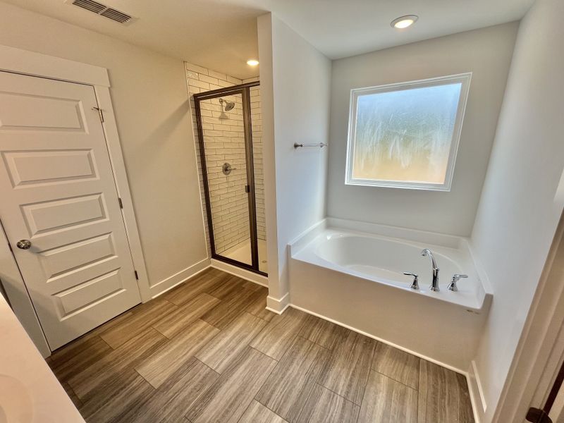 Glamour bath with tile shower and large privacy window above garden tub.