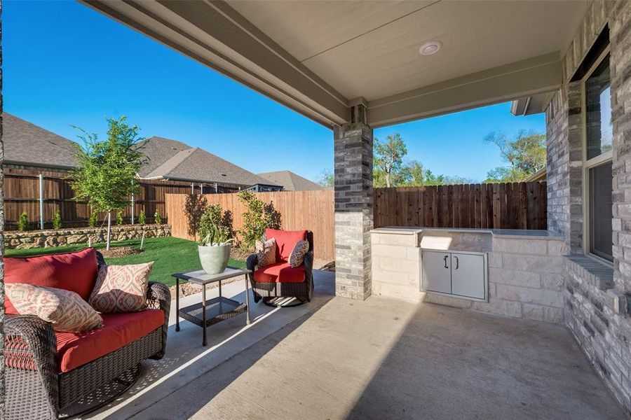 View of extended patio featuring built-in grill with granite countertop and stainless steel doors