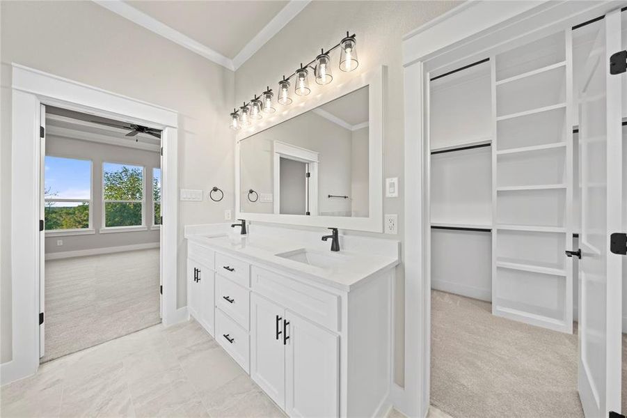 Full bathroom with light carpet, double vanity, a walk in closet, and crown molding