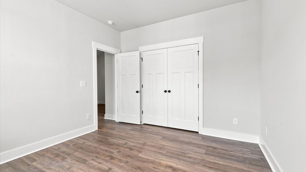 Superior hardwood flooring enhances the comfort and style of this secondary bedroom near Lake Bowen
