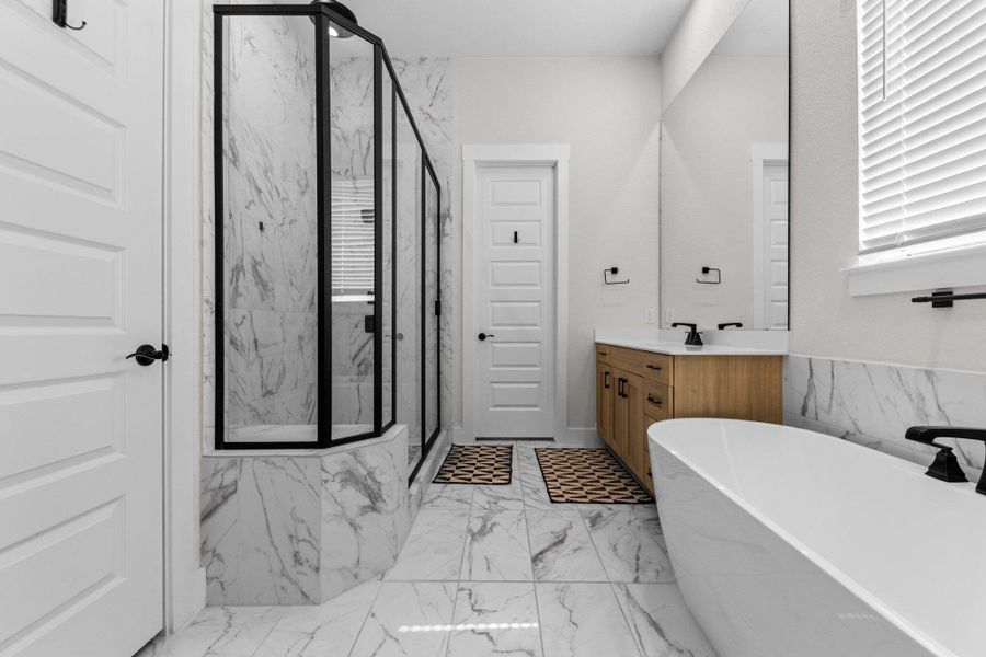 Bathroom with marble finish floor, a soaking tub, a marble finish shower, and vanity