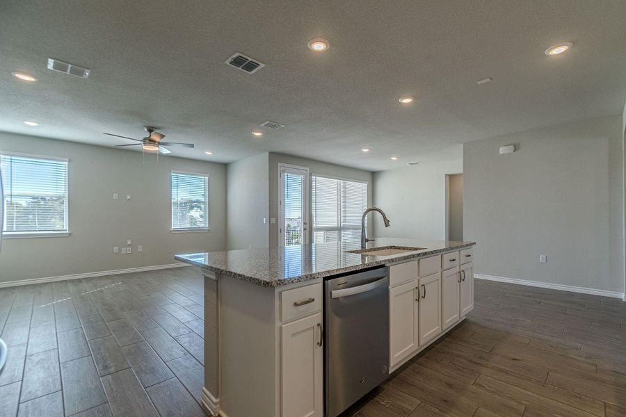 Kitchen featuring dark wood-style flooring, light stone countertops, white cabinets, stainless steel dishwasher, and recessed lighting Kitchen featuring dark wood-style flooring, light stone countertops, white cabinets, stainless steel dishwasher, and recessed lighting