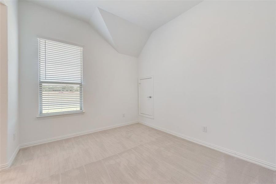 Carpeted spare room with vaulted ceiling