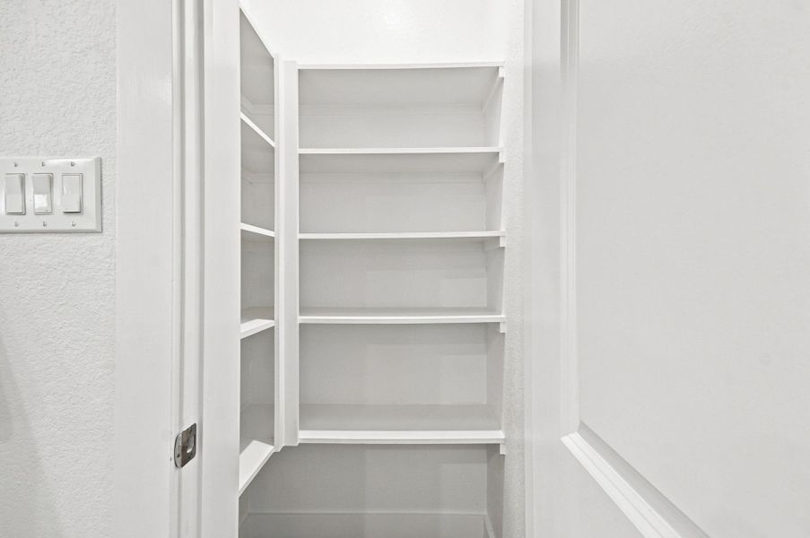 Convenient walk-in pantry with built-in shelving, providing plenty of organized storage for groceries and kitchen essentials. Convenient walk-in pantry with built-in shelving, providing plenty of organized storage for groceries and kitchen essentials.