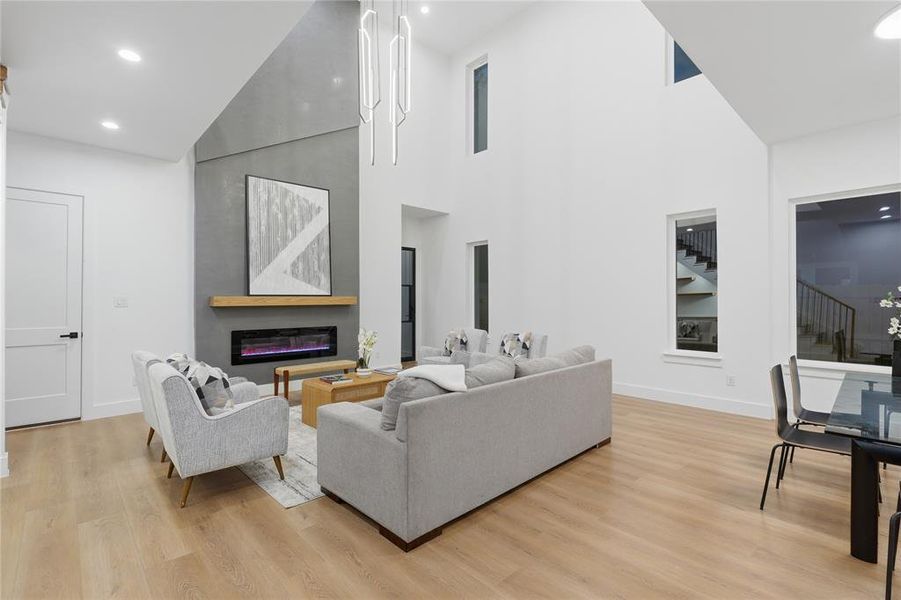 Vaulted ceiling living area featuring a modern fireplace with a concrete-finish surround, light wood mantel, and an inset linear electric fireplace Vaulted ceiling living area featuring a modern fireplace with a concrete-finish surround, light wood mantel, and an inset linear electric fireplace