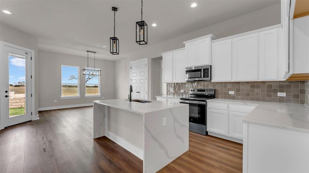 Polished stone countertops and rich wood floors anchor this open concept kitchen design. Polished stone countertops and rich wood floors anchor this open concept kitchen design.