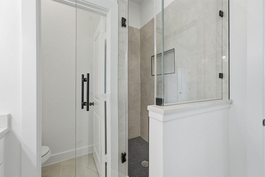 Because you deserve a shower that feels like a destination. Large-format tile surround, a built-in niche, matte black hardware, rain shower head, bold frameless glass, and contrasting penny tile floor come together in a primary bath that rivals any boutique hotel. Because you deserve a shower that feels like a destination. Large-format tile surround, a built-in niche, matte black hardware, rain shower head, bold frameless glass, and contrasting penny tile floor come together in a primary bath that rivals any boutique hotel.