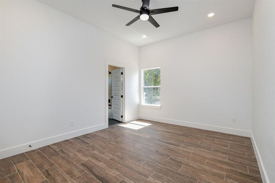 Spare room with a ceiling fan, baseboards, and dark wood-style floors