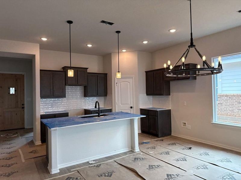 Kitchen featuring a central island, dark wood-finish cabinetry, light-toned subway tile backsplash, and recessed lighting