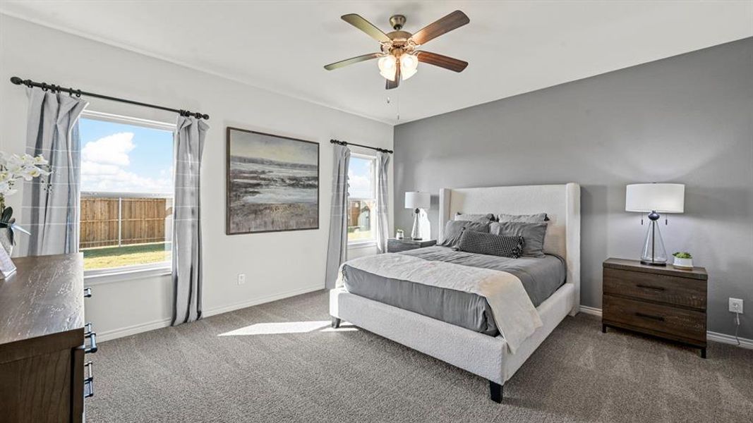 Spacious bedroom featuring neutral carpeting, a dual-pane window offering exterior views, and a ceiling fan with integrated lighting Spacious bedroom featuring neutral carpeting, a dual-pane window offering exterior views, and a ceiling fan with integrated lighting