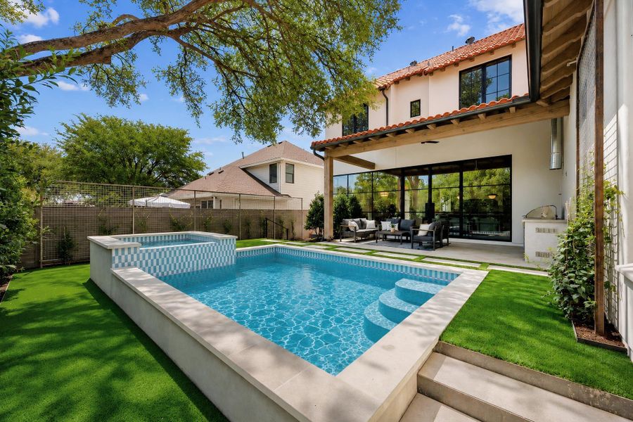 An inviting backyard oasis centers around a geometric swimming pool framed by manicured turf.