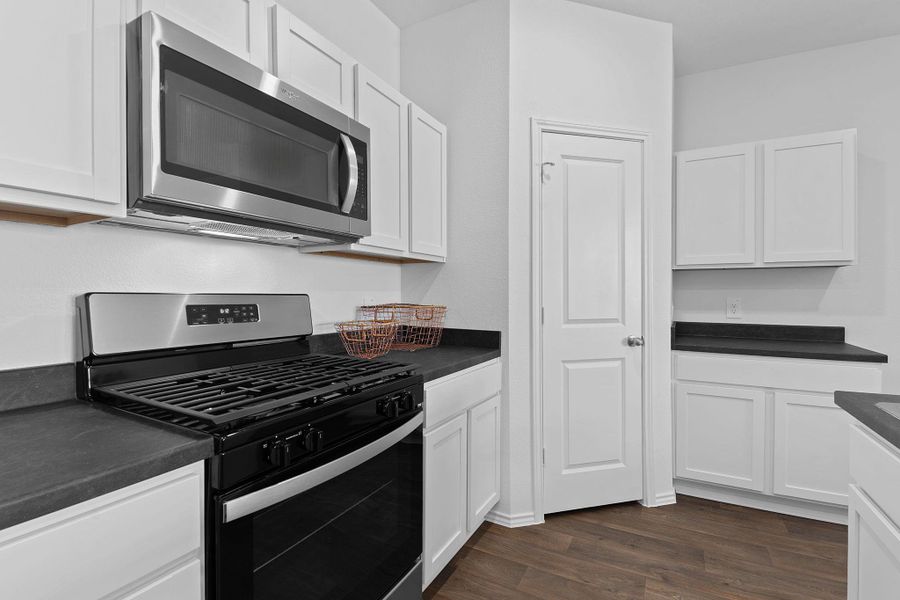 Kitchen featuring appliances with stainless steel finishes, dark countertops, and white cabinets