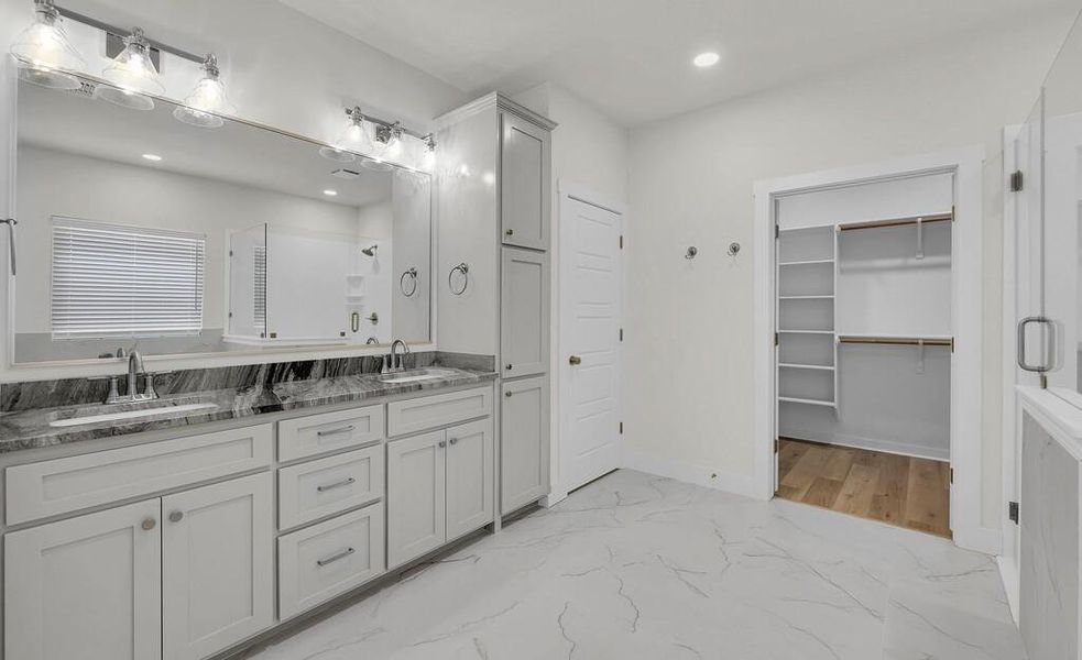 Full bath featuring light marble finish floors, a shower stall, double vanity, recessed lighting, and a spacious closet