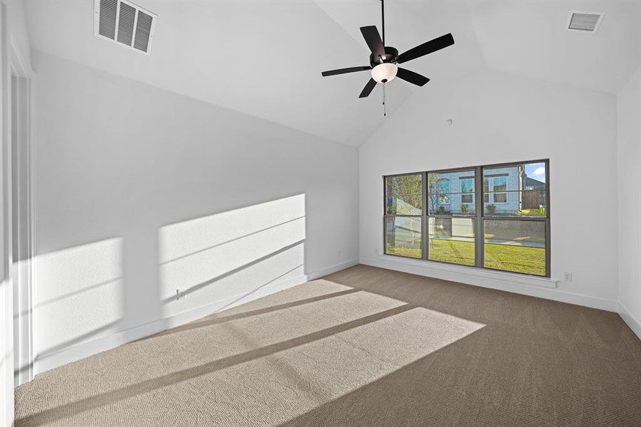Carpeted empty room featuring ceiling fan and high vaulted ceiling Carpeted empty room featuring ceiling fan and high vaulted ceiling