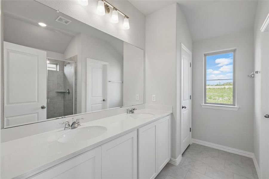 Full bath featuring double vanity, a tile shower, and marble finish floors Full bath featuring double vanity, a tile shower, and marble finish floors