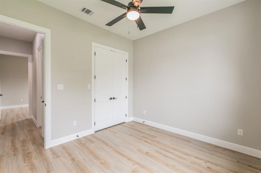 Unfurnished bedroom with light wood-style flooring, baseboards, a closet, and ceiling fan Unfurnished bedroom with light wood-style flooring, baseboards, a closet, and ceiling fan