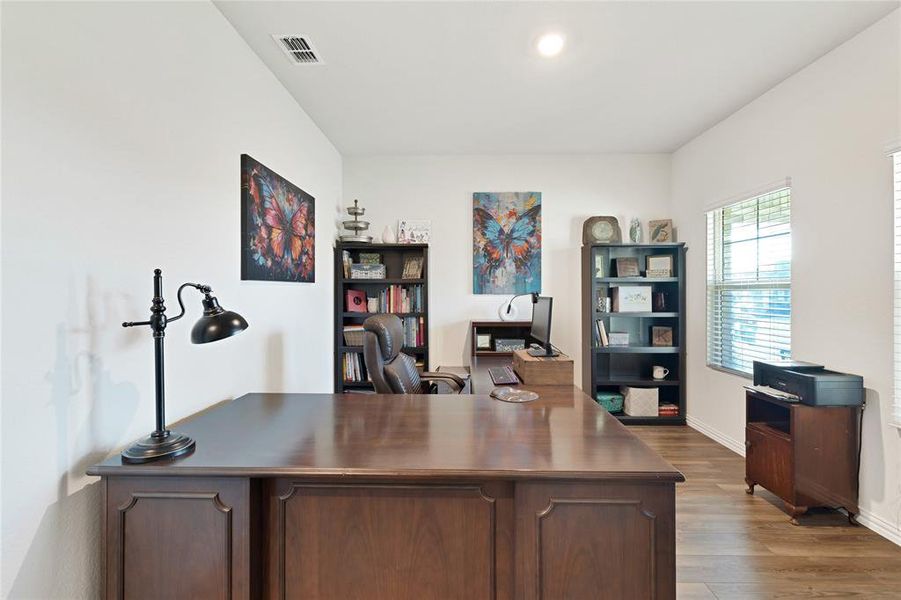 Office area with visible vents, baseboards, and wood finished floors