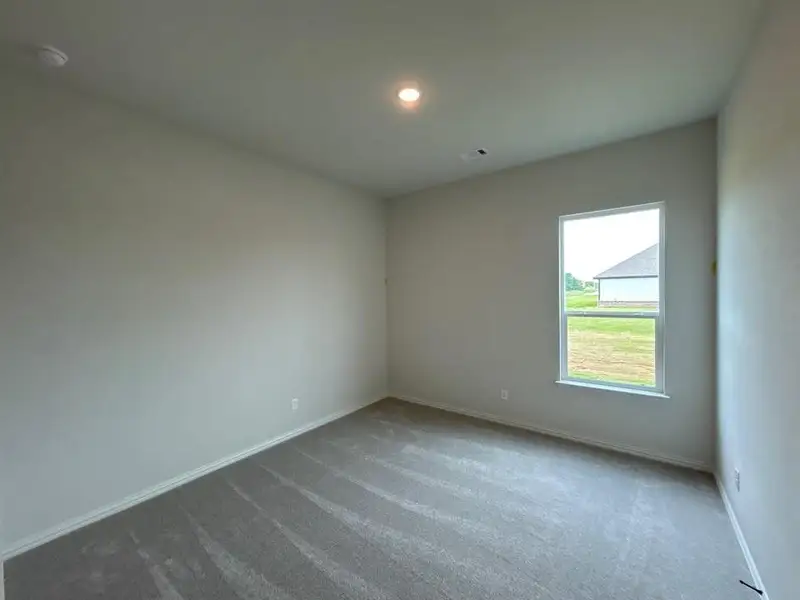 Carpeted room with a double-hung window, recessed ceiling light, and baseboard trim