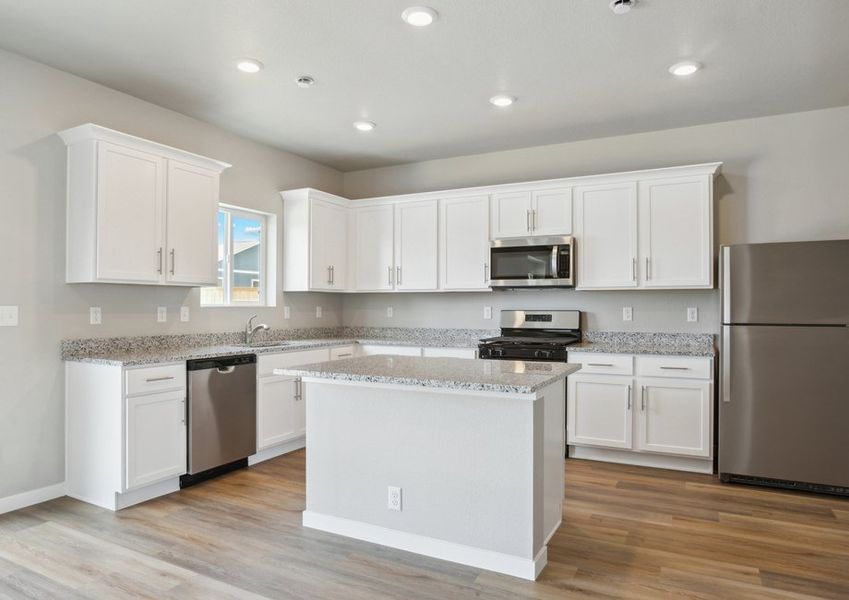 The kitchen has stainless steel appliances and plank flooring.