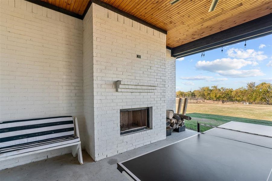 View of patio with an outdoor brick fireplace