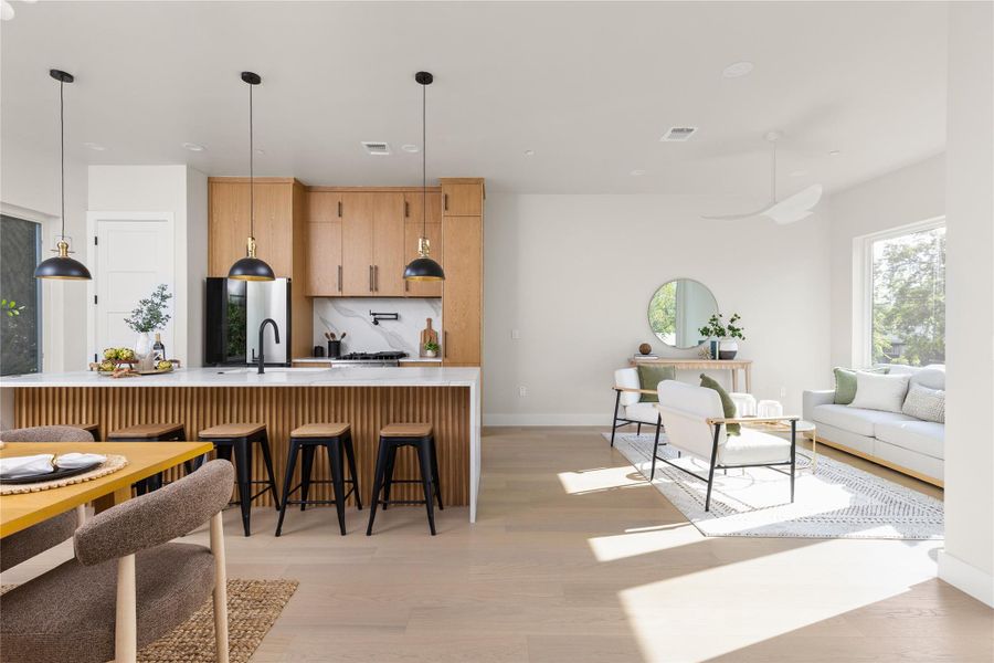 Light hardwood floors run through this airy open layout connecting the kitchen and living areas.