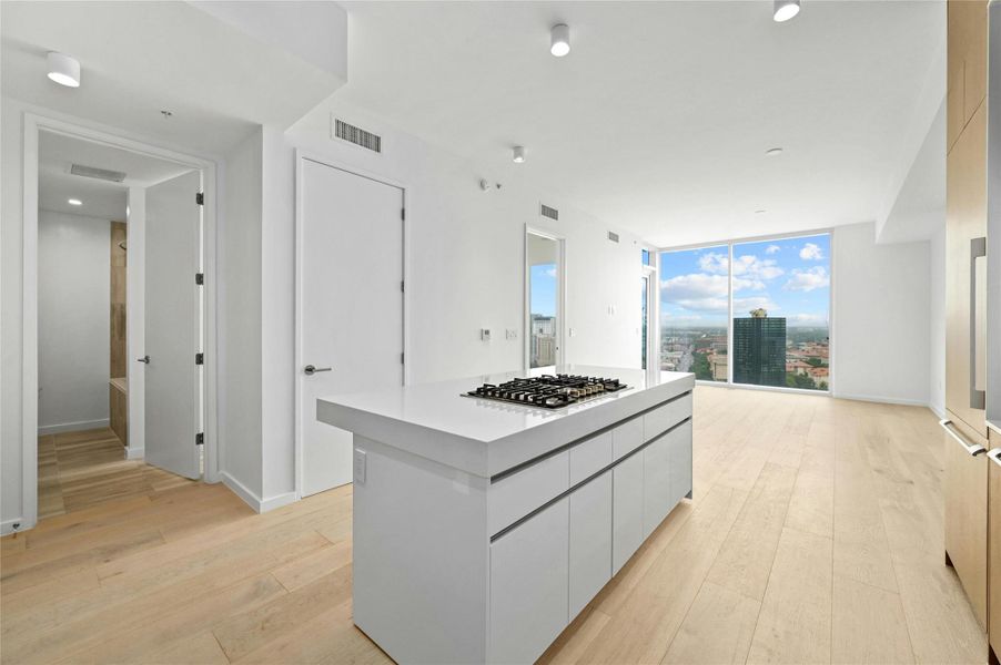 Expansive open-concept design with a Silestone® island and integrated Bosch® appliances, blending kitchen and living seamlessly. Floor-to-ceiling windows showcase dramatic skyline and UT Tower views, filling the space with natural light. Wide-plank oak floors add warmth and continuity throughout. Expansive open-concept design with a Silestone® island and integrated Bosch® appliances, blending kitchen and living seamlessly. Floor-to-ceiling windows showcase dramatic skyline and UT Tower views, filling the space with natural light. Wide-plank oak floors add warmth and continuity throughout.