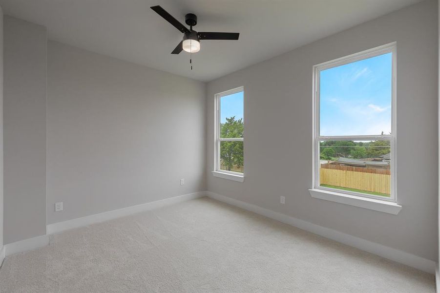 Empty room with baseboards, light colored carpet, and ceiling fan