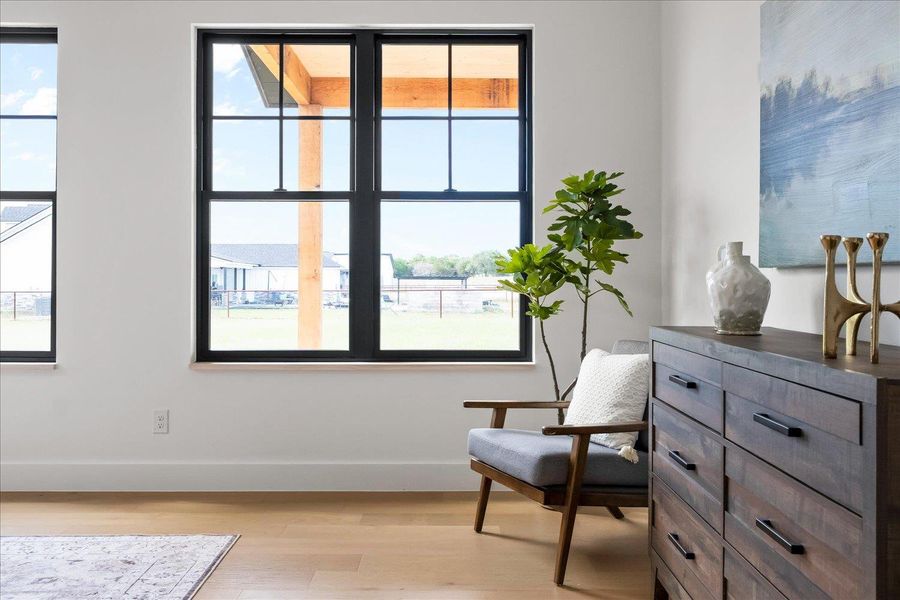 Sitting room featuring light wood-type flooring, baseboards, and healthy amount of natural light